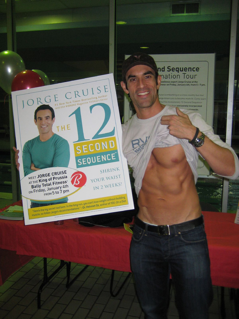 Jorge Cruise beside the Bally Total Fitness 12-Second Sequence tour poster with the red B logo